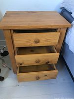 Front view of the wood side table with all three drawers partially open showing interior and drawer fronts