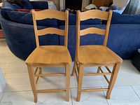 Front view of two wooden stools showing square seats and ladder backs