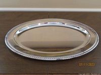 Top view of the polished silver plated oval tray showing the decorative border detail and reflective surface.