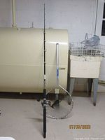 Penn GTO 220 fishing rod standing upright next to Ranger fishing net with metal frame and black mesh, against indoor setting.