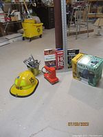 Yellow safety helmet, two staplers with staples, workshop books, drywall T-square, boxed Wagner Power Painter