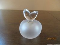Front view of Lalique frosted glass perfume bottle shaped like an apple with leaf stopper.