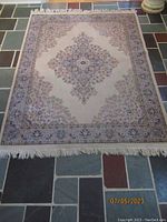 Full view of the rectangular cream rug laid on tile flooring showing its overall design and fringed edges.