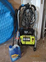 Full front view of Ryobi pressure washer with hose coiled and Zep jug at base