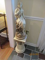 Full view of statue seated on pedestal against wall