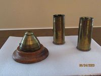 Photo showing WWI brass fuze cap No. 85-I and two WWII brass shell casings.