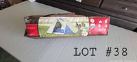 Photo of folded 4 person dome tent inside brown storage bag showing product image and model info.