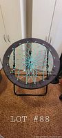 Front view of black and blue bungee chair showing turquoise bungee cord circular woven seat and black frame.