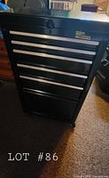 Front view of closed black metal rolling toolbox with five drawers and bottom storage area.