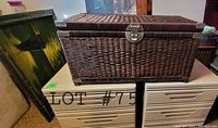 Image of dark brown wicker chest with metal corners and latch placed on two side-by-side filing cabinets.