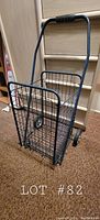 Photo of navy blue foldable metal grocery cart from angled side showing basket, handle, and wheels.