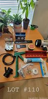 Photo of assorted home and hardware items on table including dual dial timer, thermometer, rope, hardware pieces and flashlight