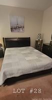 Full view of queen size bed with the lightweight grey quilt blanket spread evenly over it showing the patchwork pattern design.