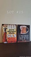 Two retro style metal beer signs shown side by side against a wall with 'LOT #25' text.