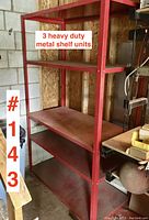 Red metal shelving unit in garage, four shelves and open frame