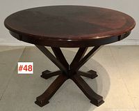 Front view of round mahogany finish parlour/dining table with four-legged pedestal base.
