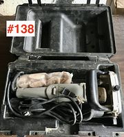 Porter Cable biscuit joiner tool stored inside a hard black plastic carrying case, showing the full tool and part of the cord, exterior and interior of case.