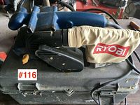 Ryobi belt sander on top of carrying case, showing the tool and dust bag.