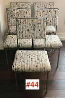 Set of five 1970s chrome framed chairs with patterned upholstered seats and backs arranged together on dark wood floor.