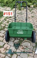 Green Scotts Turf Builder Classic Drop spreader with accessories arranged on a stone patio.