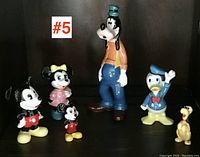Front view of the full set of six vintage Disney ceramic figurines showing Mickey, Minnie, Mini Mickey, Goofy, Donald Duck, and Pluto lined up.