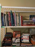 Three-tier wire shelf loaded with art, history and travel books; top shelf with upright volumes and side-by-side titles