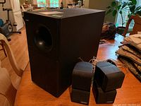 Photo showing black ported enclosure subwoofer and four black cube satellite speakers with Bose logos.