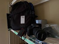 Overview showing Lowepro bag, Canon camera with attached lens, plastic-wrapped additional lens and box.