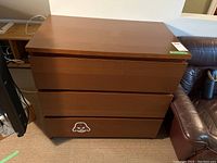 Front view of a three-drawer wooden dresser with a Darth Vader style sticker on the bottom drawer showing overall condition and design.