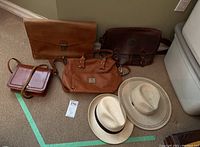 Photo showing all items: two hats, two leather satchels, two purses laid on floor.