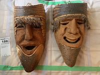 Front view of both vintage Oaxaca wooden dance masks side by side showing facial detail and natural materials