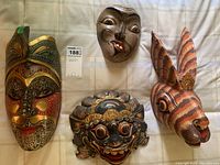 All four hand carved wood masks together on a cloth background, showing size and variety
