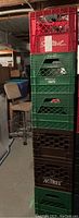 Stack of six plastic milk crates in red, green, and brown, stacked in basement setting.