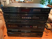 Full view of stacked Pioneer stereo units on wooden table showing the front panel of all components including cassette deck, CD player, stereo receiver, and tuner.