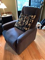 Front view of the electric recliner chair in dark fabric with a patterned throw pillow placed on the seat.