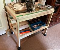 Wood work table with white paint, two shelves, side rails, and caster wheels shown from a side angle.