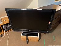 Front view of the Sony Bravia 42-inch flatscreen TV with remote placed below fan on a wooden box.
