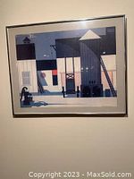 Framed colorful architectural art print featuring geometric buildings and water pump, signed by John E. Bradley.