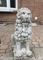 Front view of one concrete lion statue showing facial details and mane.