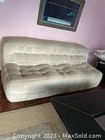 Full view of 78" wide tufted couch on parquet floor against pink wall