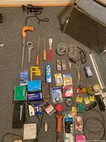 Photo showing multiple hand tools including screwdrivers, wrenches, c clamps, and containers with screws and fasteners