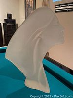 Profile view of frosted lucite lady sculpture on a pool table.