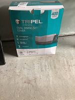 Photo showing original box for Tripel Oval Dining Set Cover Large Size, highlighting water resistance, fade resistance, weather resistance to -25°C, and 2 year warranty.