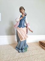 Full view of the Lladro lady figurine standing upright on carpet with minor chip visible on the base