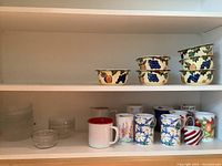 Shelf with six Dansk pottery bowls featuring fruit designs, stacked in two groups.