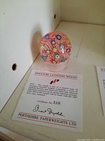 Front view of colorful miniature latticinio paperweight with certificate
