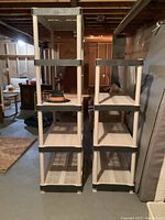 Two shorter resin shelves side by side, showing black corner supports and perforated beige shelving surfaces.