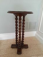 Full view of wood round side table showing three barley twist legs and cross base on carpet.