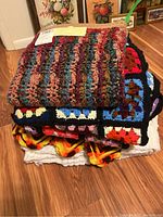 Stack of four handmade afghans showing different colors and patterns