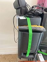 Two Bose satellite speakers stacked on top of a Bose subwoofer with cables and remote on top.